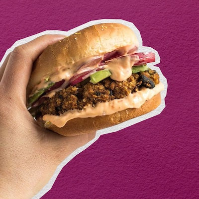 An image of a hand holding a vegan bean burger