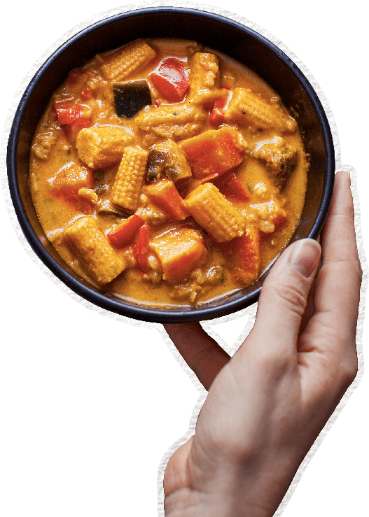 Hand holding bowl of vegan Thai curry